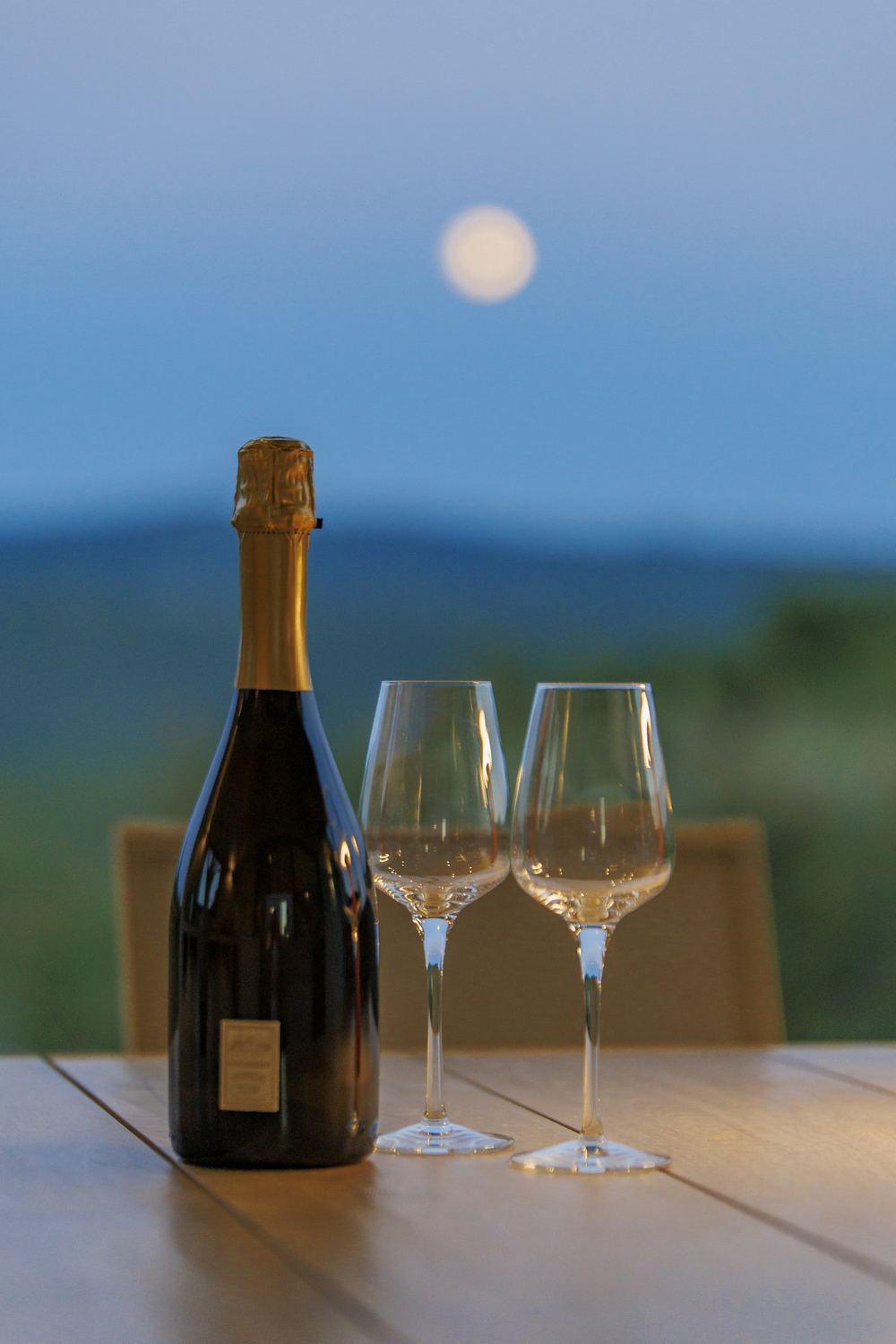 Sparkling wine and two glasses on the terrace under the moon